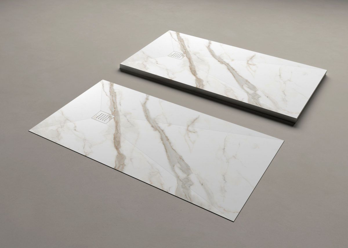 Due piastrelle rettangolari in marmo con venature marroni su una superficie grigia.