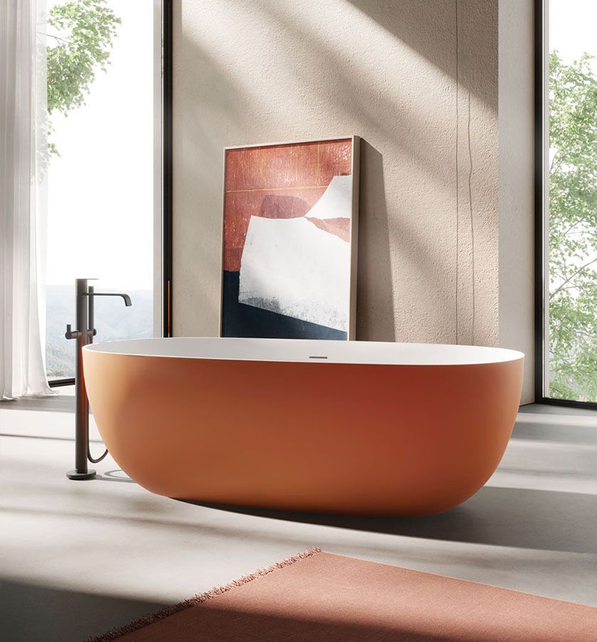Vasca da bagno arancione indipendente con rubinetto scuro, opere d'arte e ampia finestra.