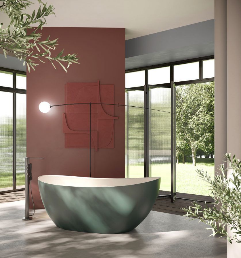 Vasca da bagno verde in un bagno moderno con pareti, finestre e piante rosse.