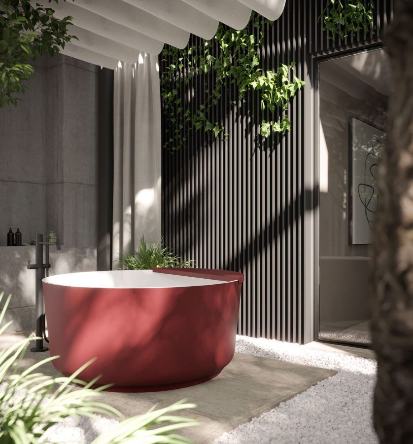 Vasca da bagno rossa in un ambiente esterno con verde e parete grigia.