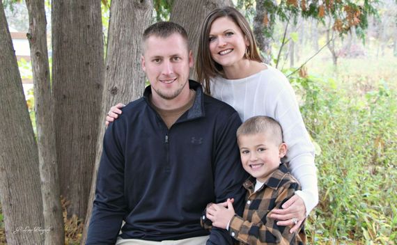 A family is posing for a picture in front of a tree.