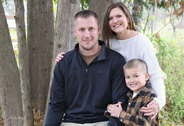 A family is posing for a picture in front of a tree.