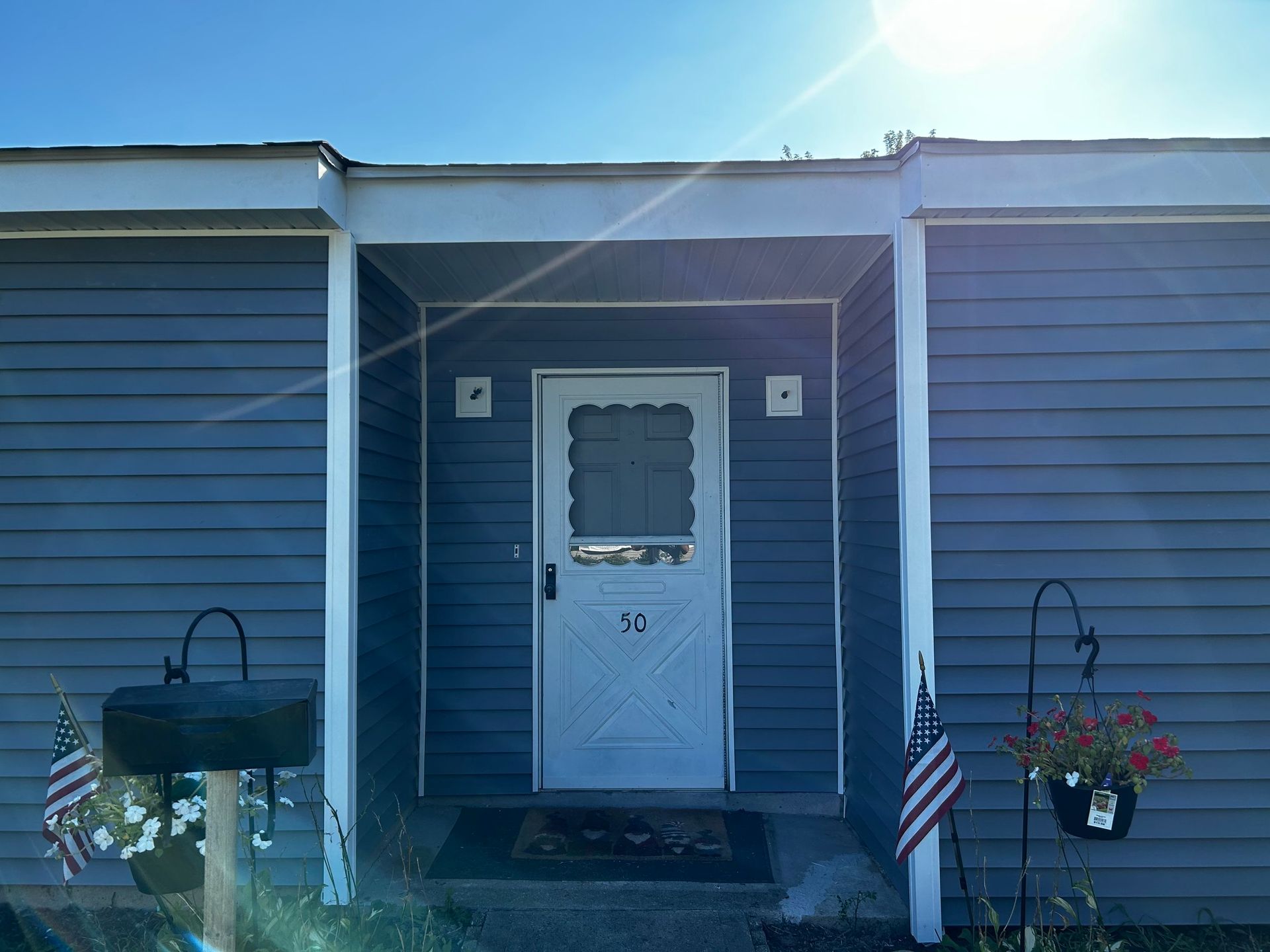 A blue house with a white door and a porch.