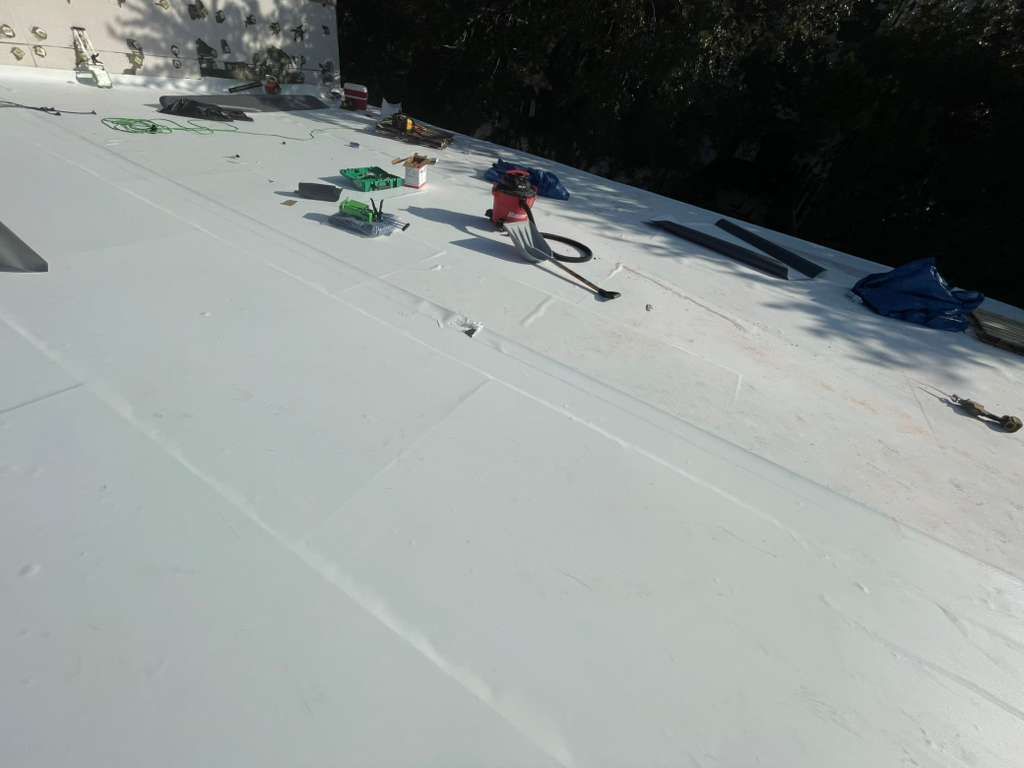 Flat roof installation in progress in Orlando FL with professional roofers applying single-ply membrane for leak prevention.