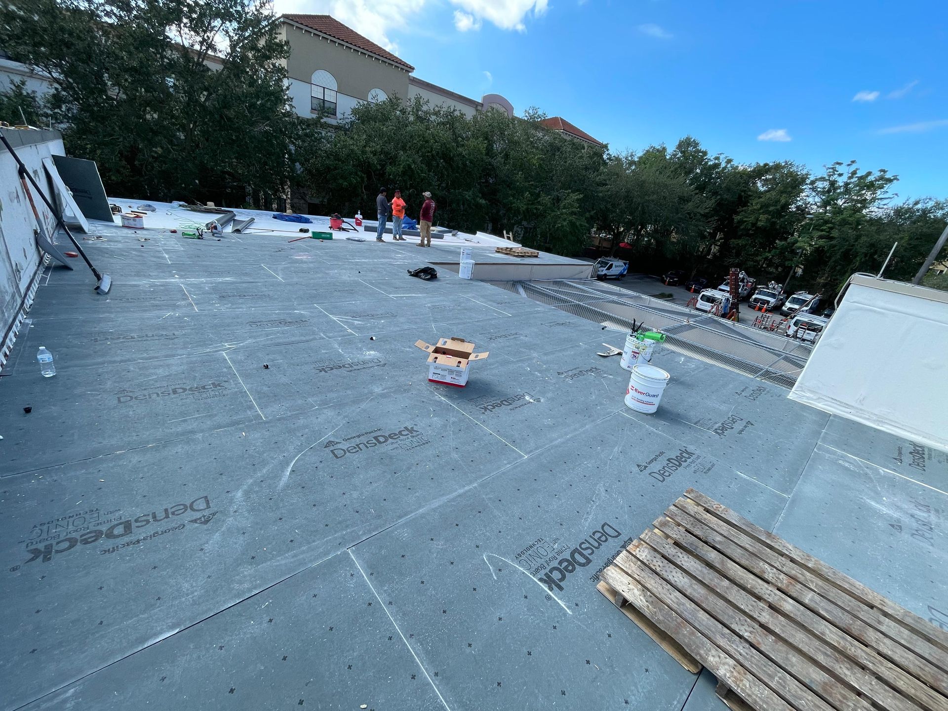 Roofing crew performing flat roof replacement in Orlando FL, applying waterproof layers for commercial building protection.
