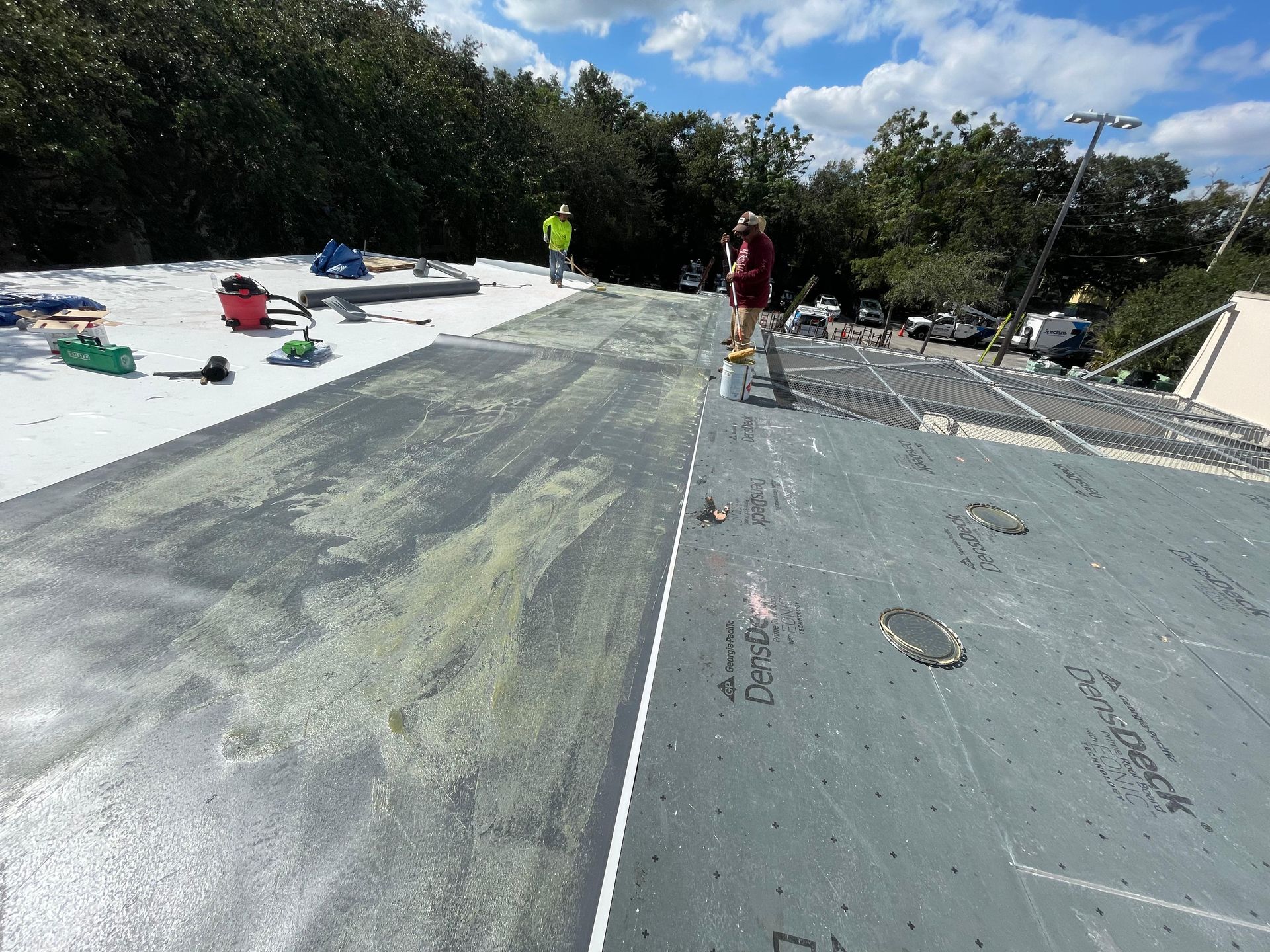 Flat roof replacement in progress in Central Florida — applying adhesive membrane and heat-sealing joints for long-lasting results.