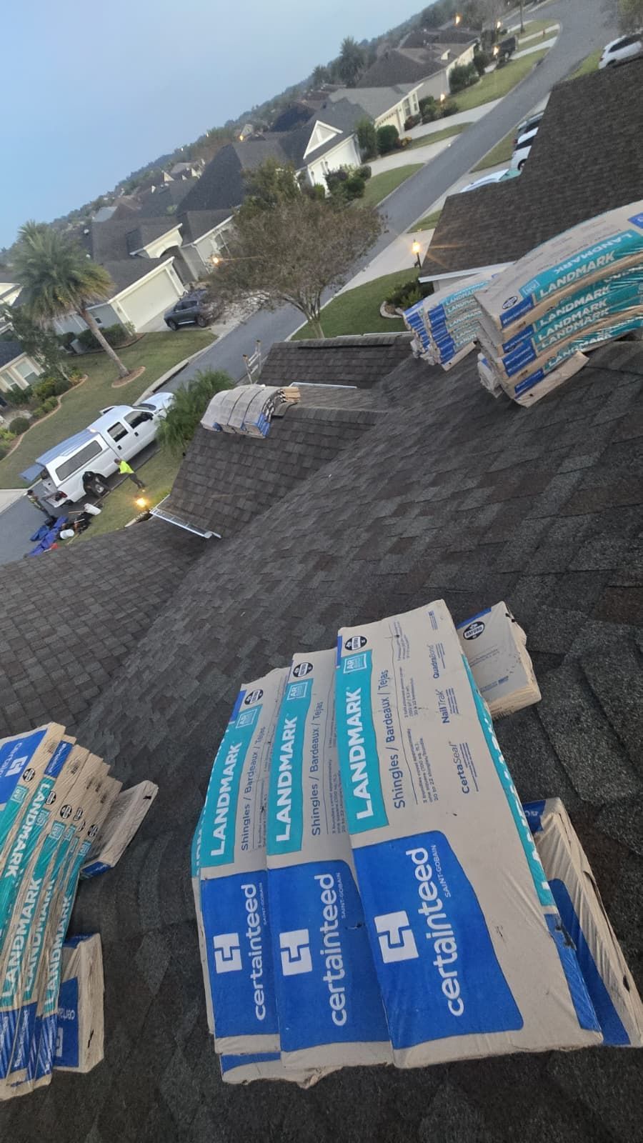 View of Casselberry neighborhood with newly installed shingle roofs and stacked roofing materials ready for installation.