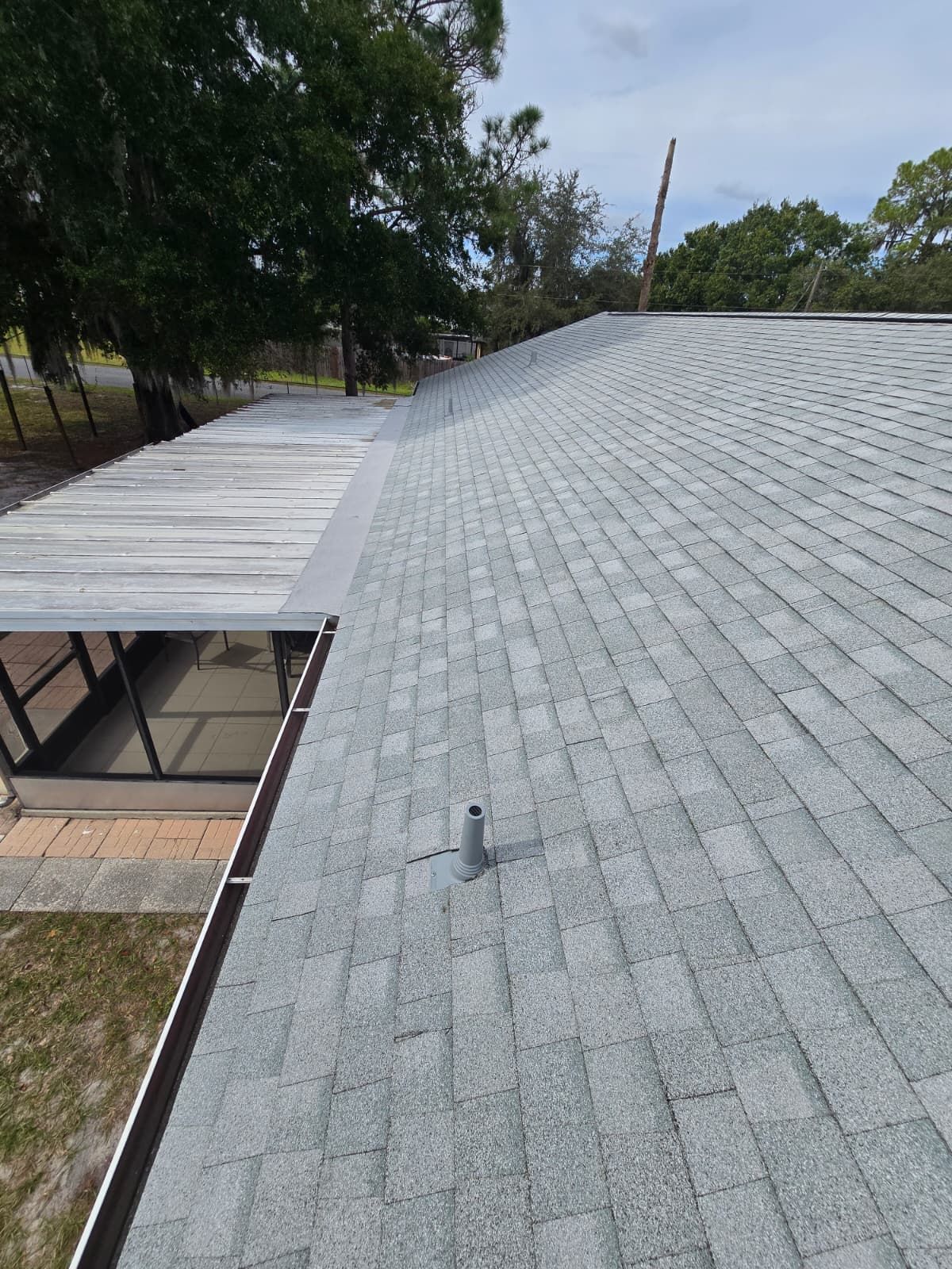 Shingle roof replacement in Lakeland Florida — newly installed gray shingles on a residential home surrounded by trees.