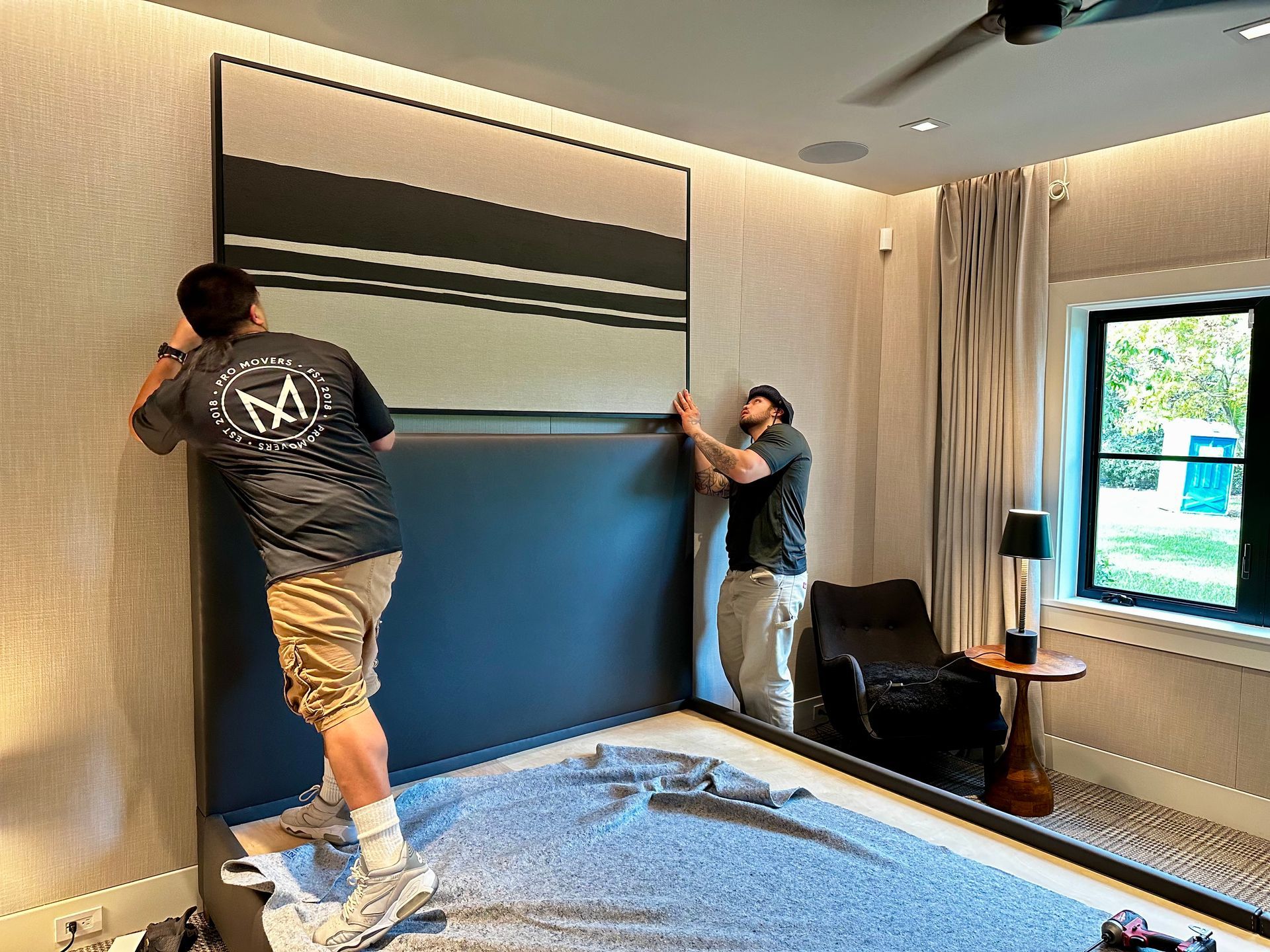 Two men are working on a wall in a room.