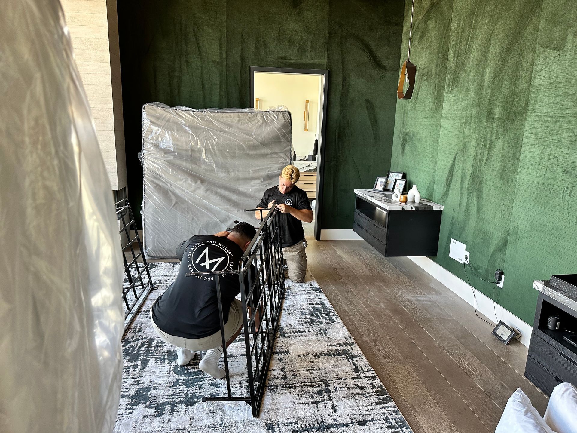 Two men are working on a couch in a living room.