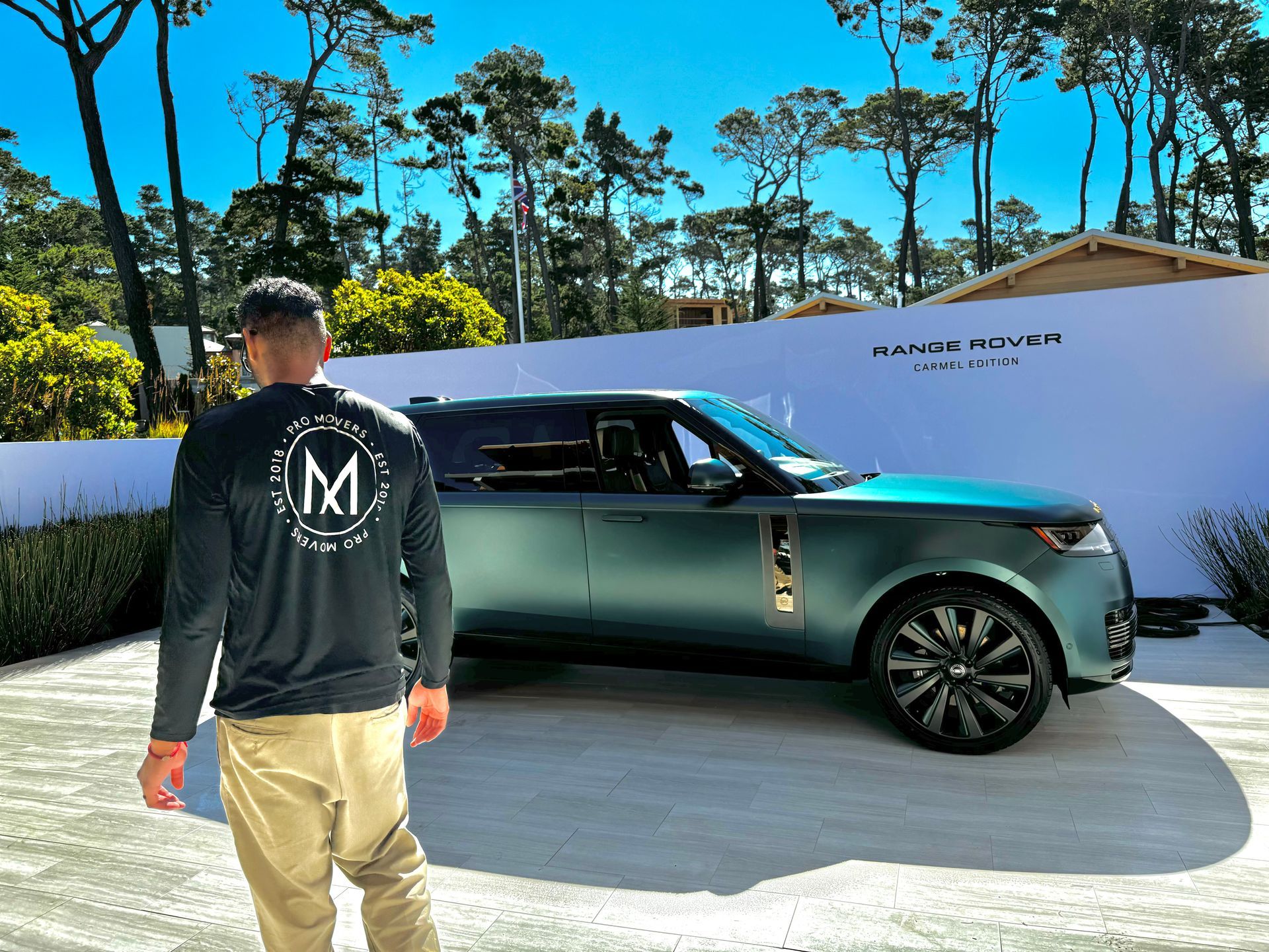 A man is standing in front of a green range rover