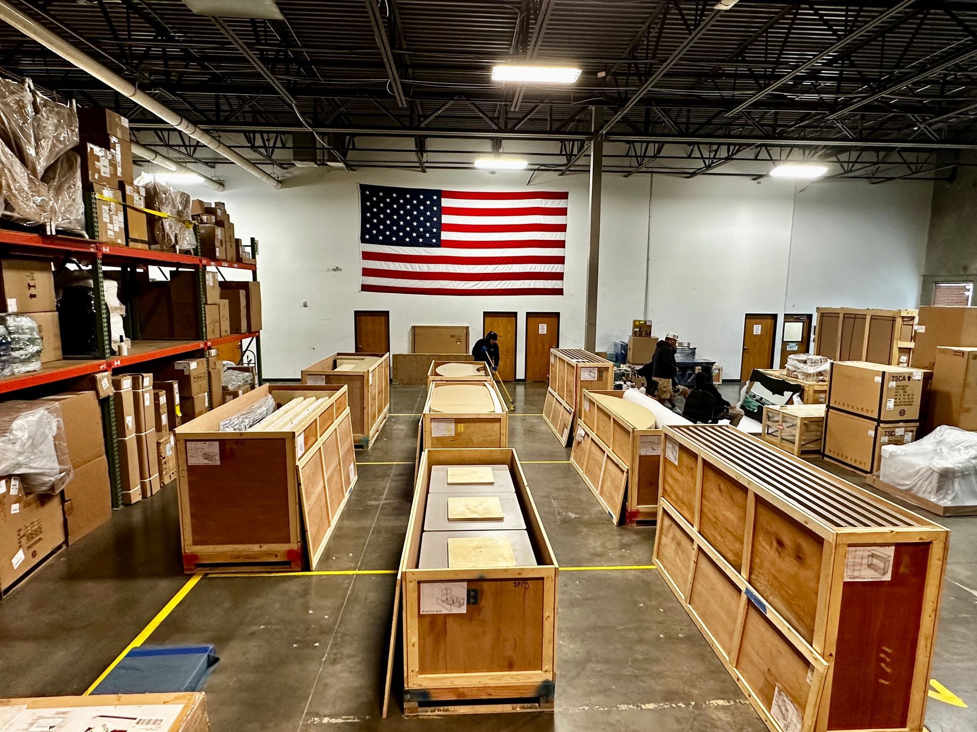 A large warehouse filled with lots of boxes and a large american flag on the wall.