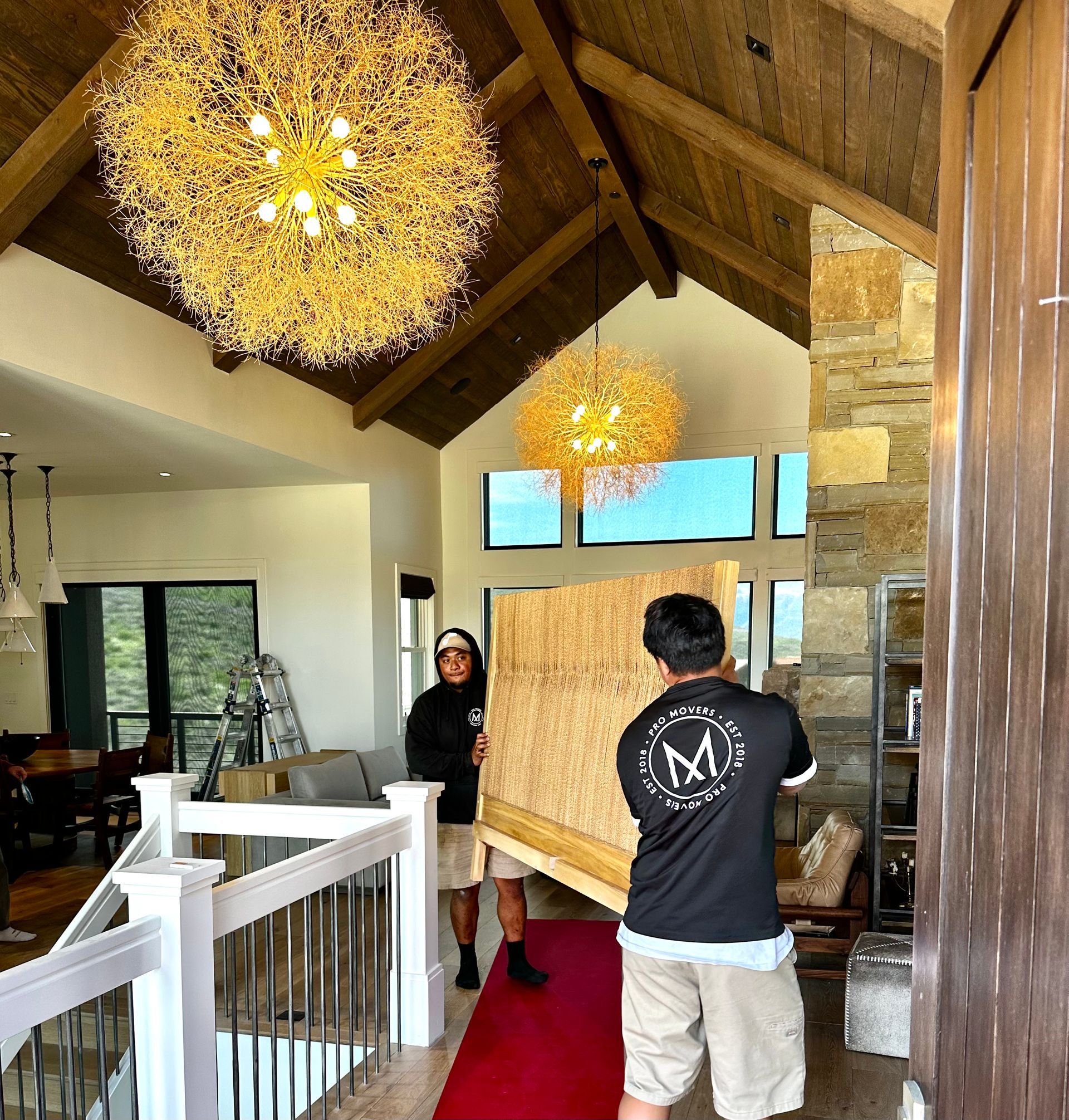 A man carrying a large piece of wood with the letter m on his back