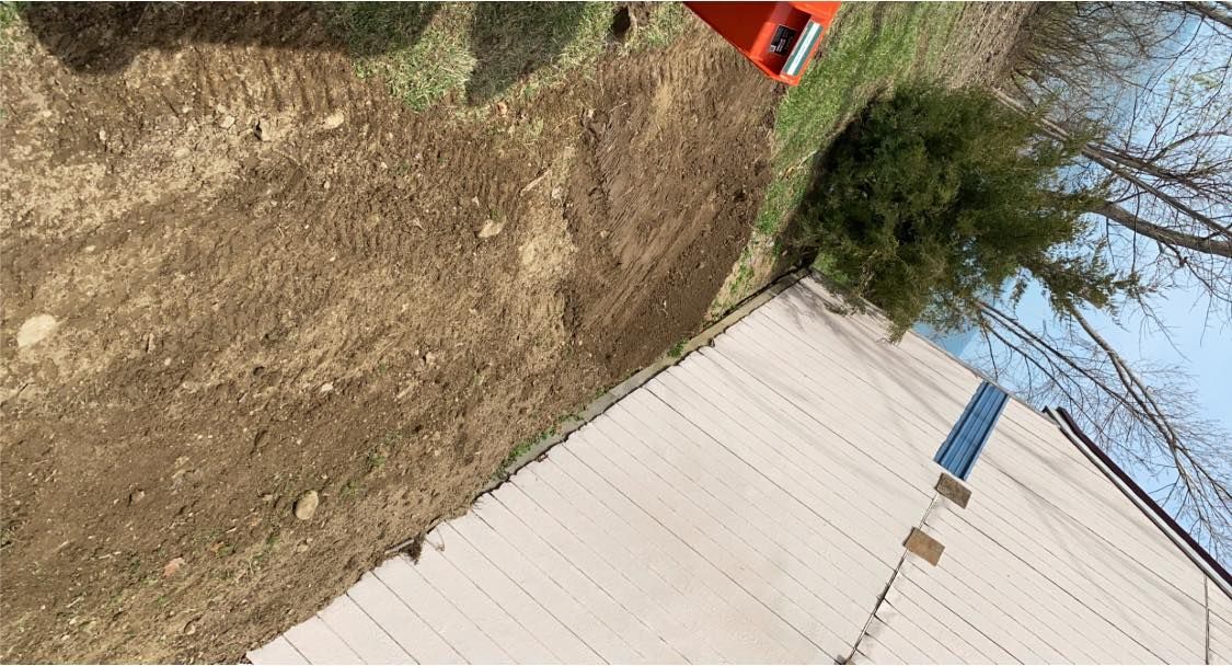 A person is walking down a dirt path next to a house.