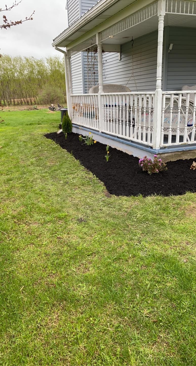 A house with a porch and a large lawn in front of it.