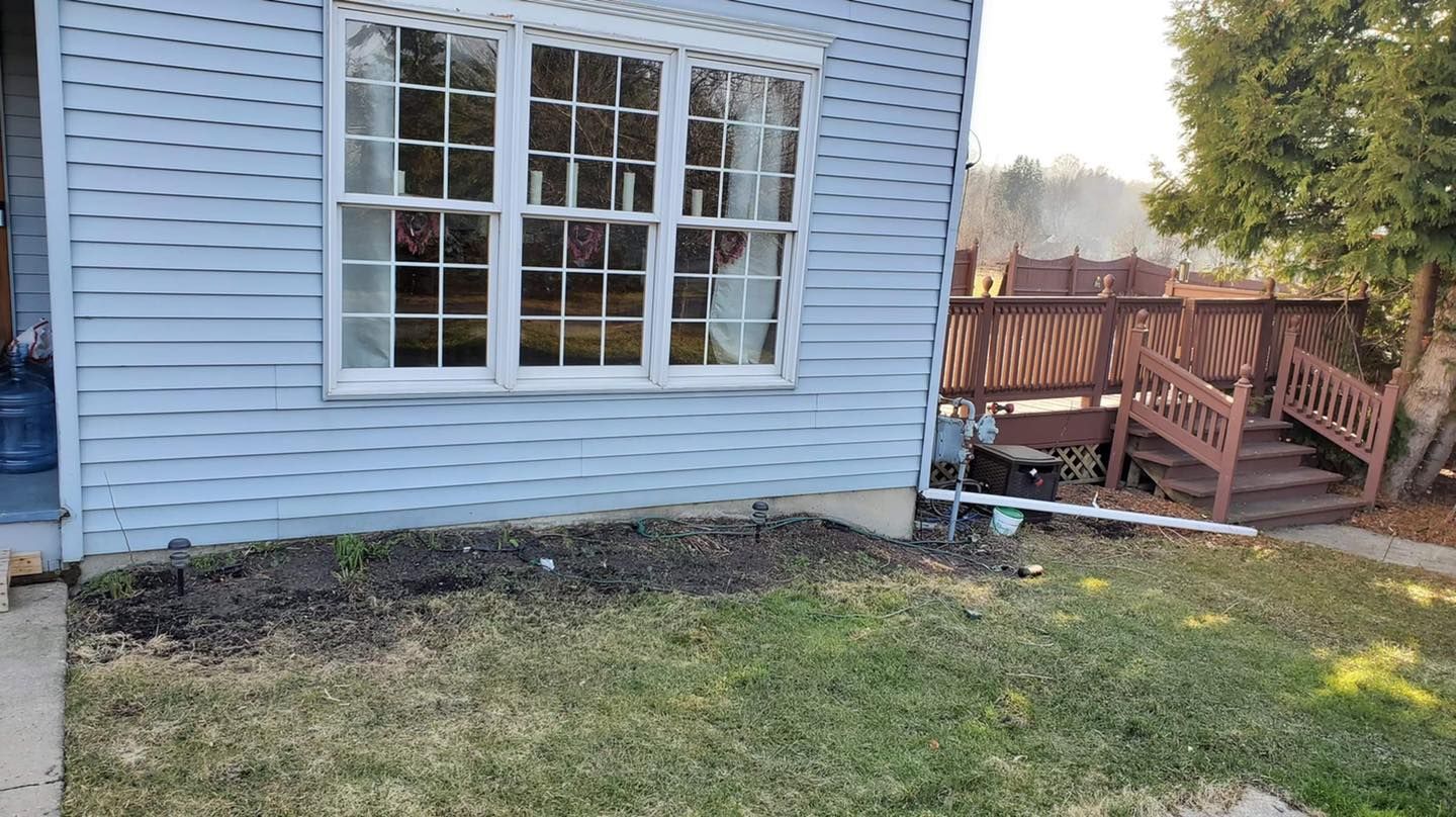 A blue house with a large window and a wooden deck.