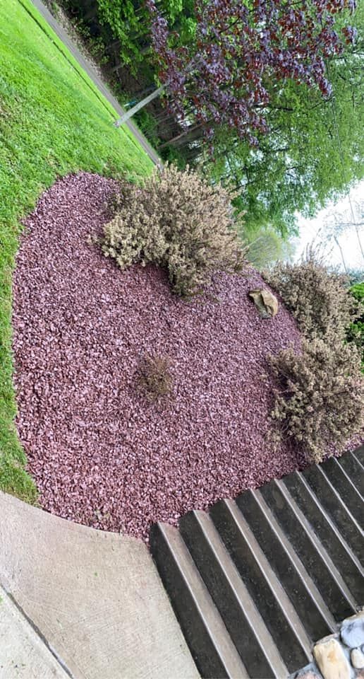 A pile of purple mulch is sitting on top of a lush green lawn next to a set of stairs.