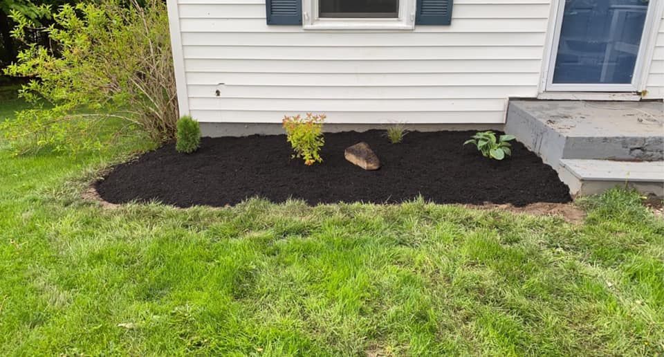 A white house with a black mulch bed in front of it.
