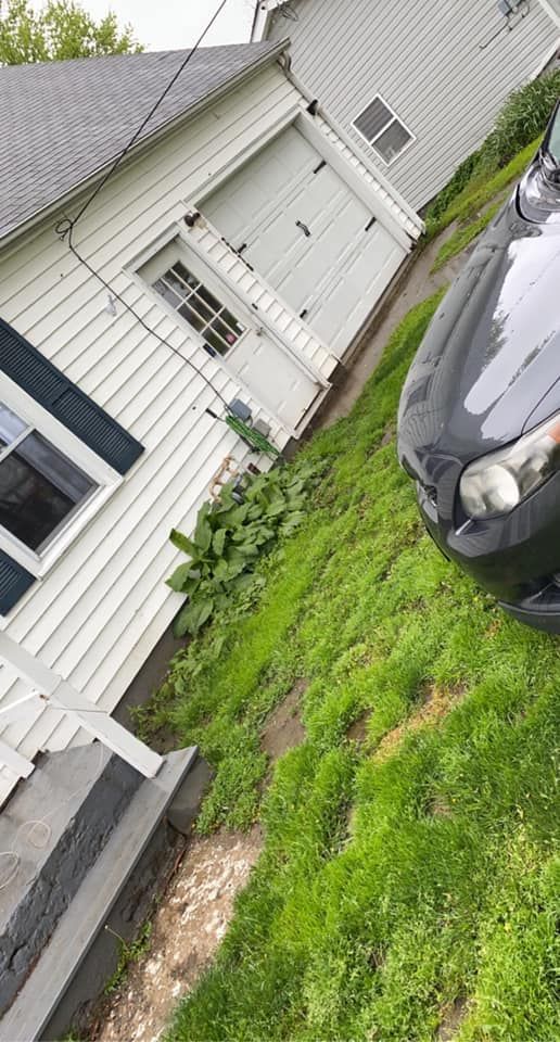 A black car is parked in front of a white house.