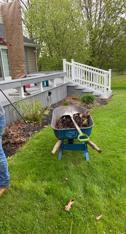 A person is pushing a wheelbarrow full of dirt in a yard.