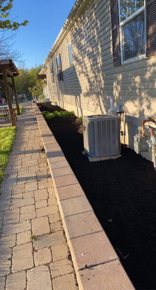 A walkway leading to a mobile home with an air conditioner on the side of it.