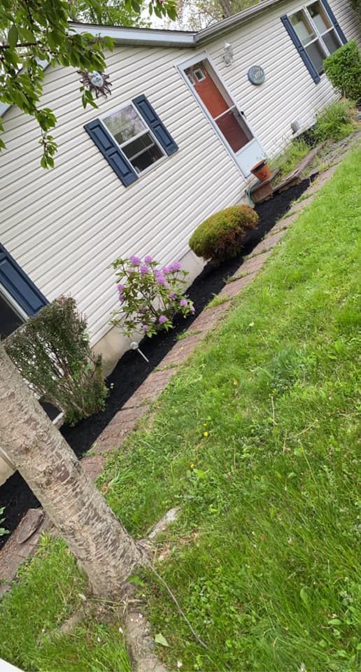 A white mobile home with blue shutters is sitting on top of a lush green lawn.