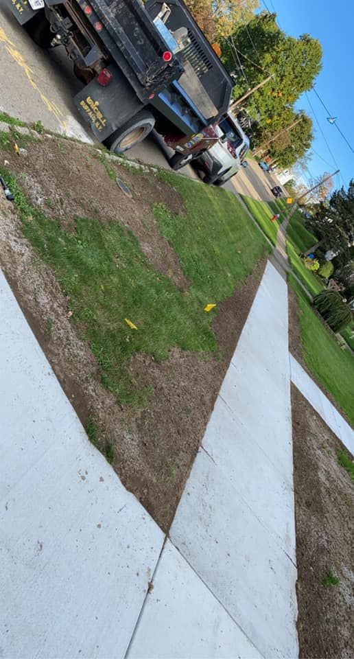 A dump truck is parked on the side of the road next to a sidewalk.