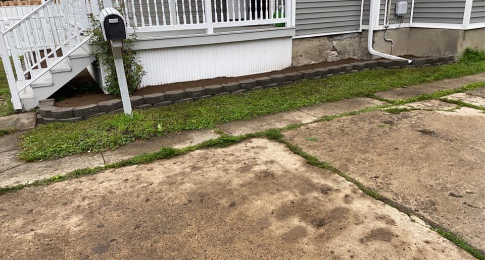 A dirty driveway in front of a house with stairs and a mailbox.