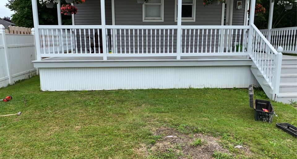A house with a porch and a lawn mower in front of it.