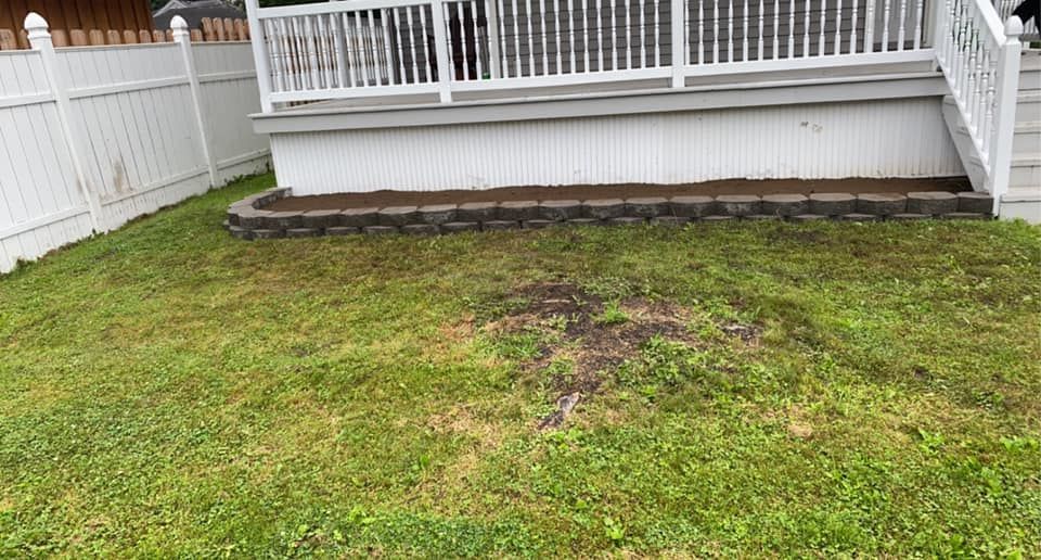 A lawn with a white fence and a deck in the background.