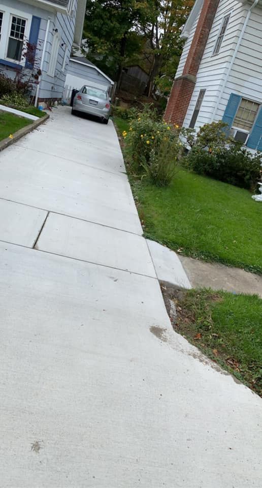 A car is parked in a driveway next to a house.