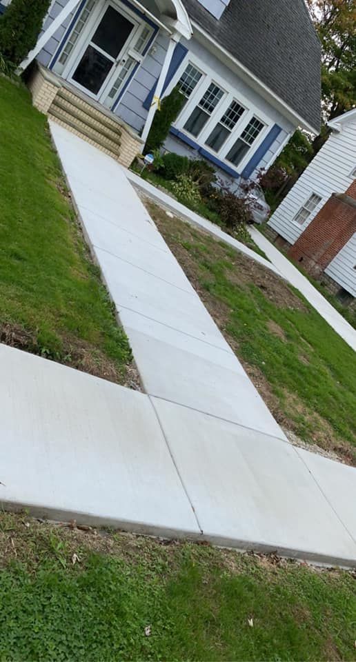 A concrete walkway leading to a house in a residential area.