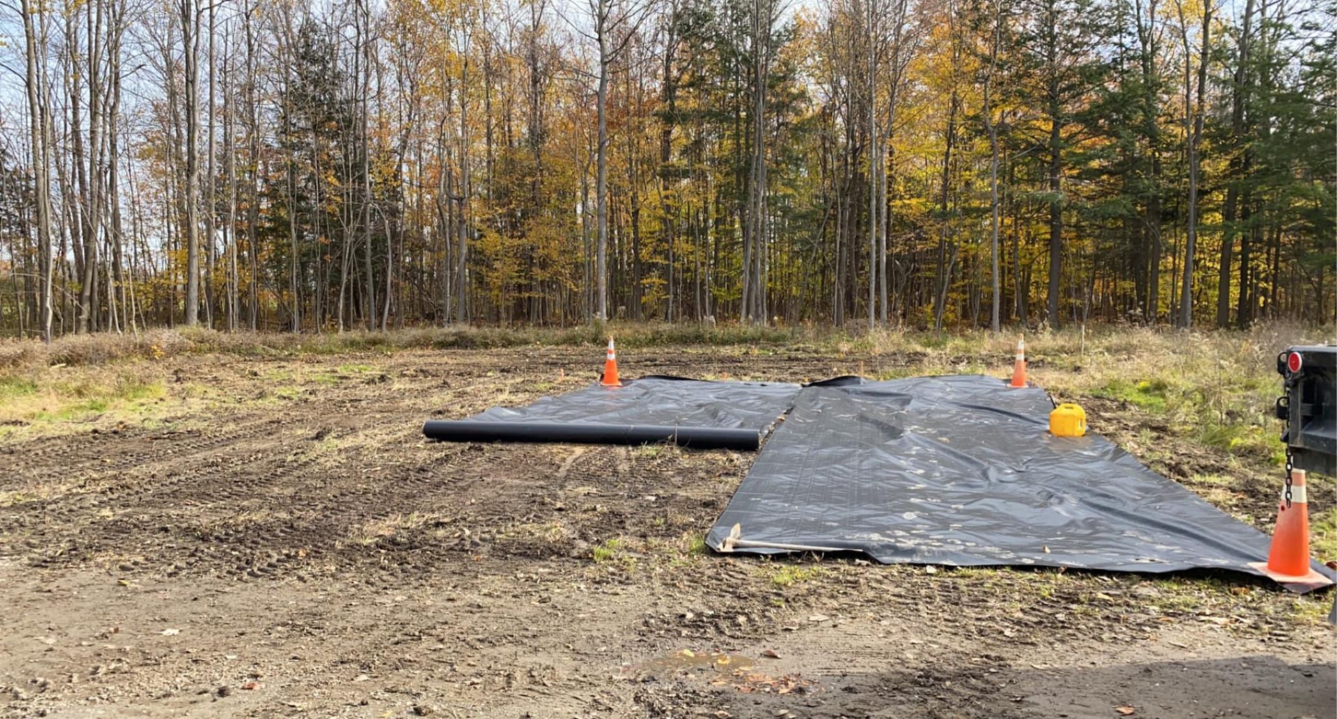 A large piece of black tarp is laying on top of a dirt field.