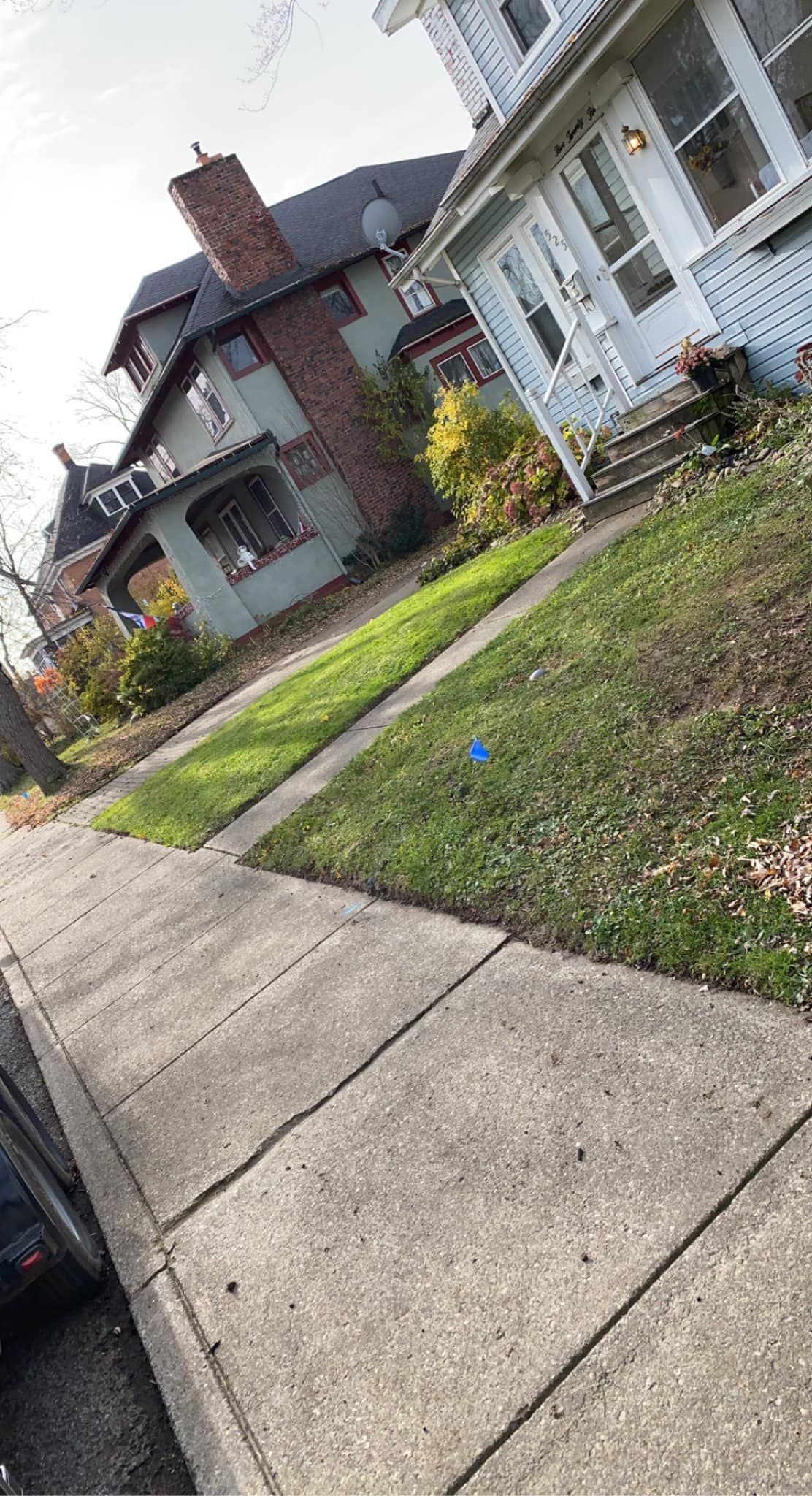 A car is parked on the sidewalk in front of a house.