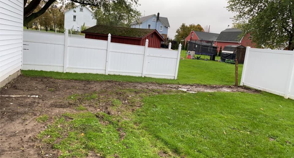 There is a white fence in the backyard of a house.
