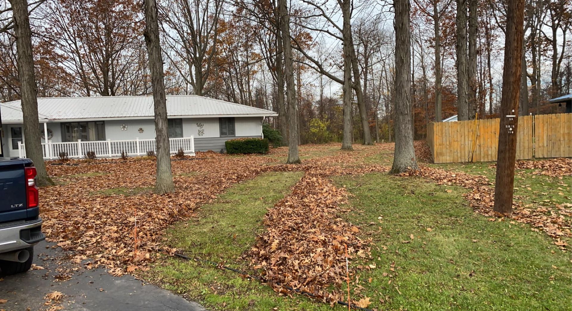 A truck is parked in front of a house in the woods.