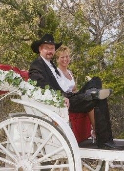 A bride and groom are sitting in a horse drawn carriage.