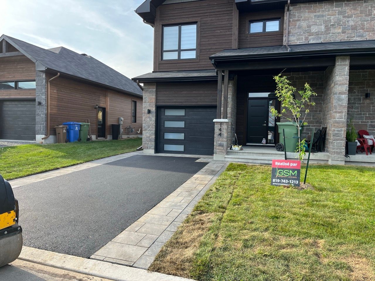 Allée nouvellement pavée devant une maison à deux étages, avec de l'herbe verte et un petit arbre dans la cour avant.