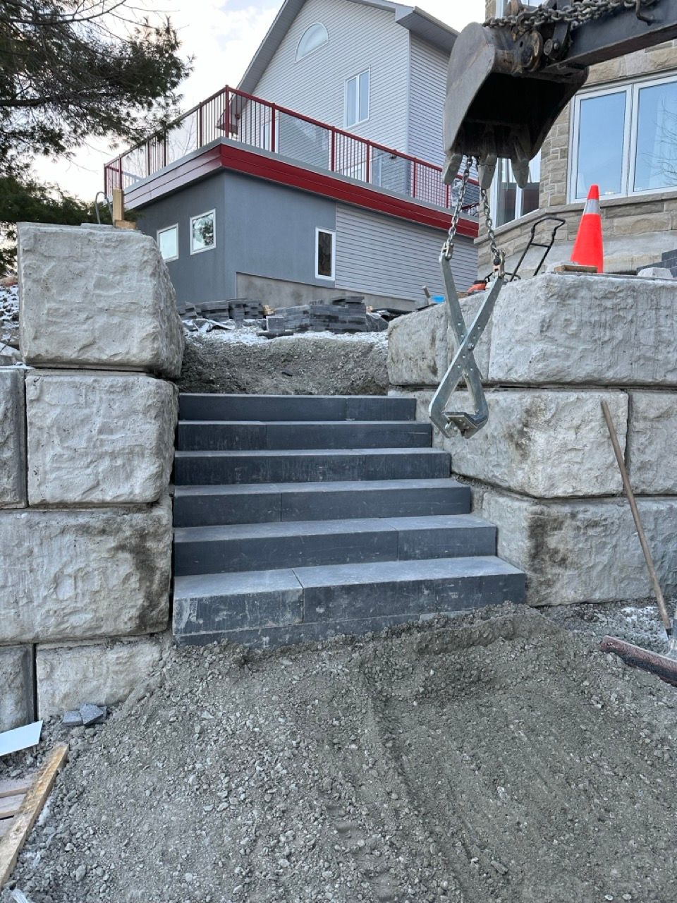Escalier en pierre menant à l'étage, flanqué de gros blocs de pierre ; chantier de construction.