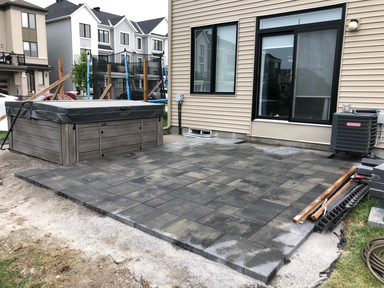 Patio avec pavés gris foncé, spa et porte coulissante en verre.