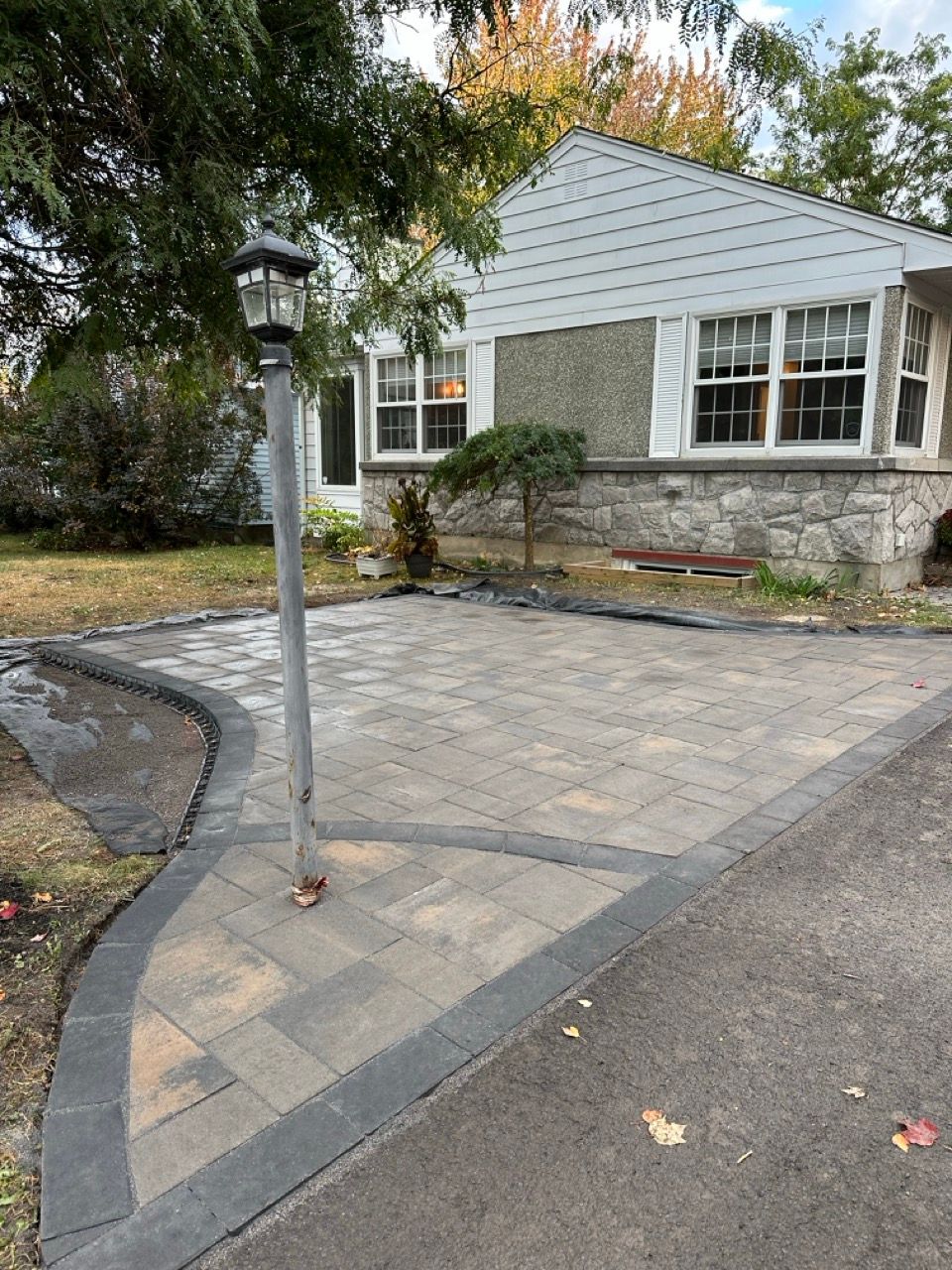 Une allée pavée devant une maison avec un lampadaire.