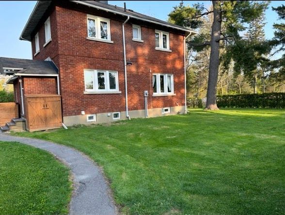 Maison en brique avec pelouse verte et allée.