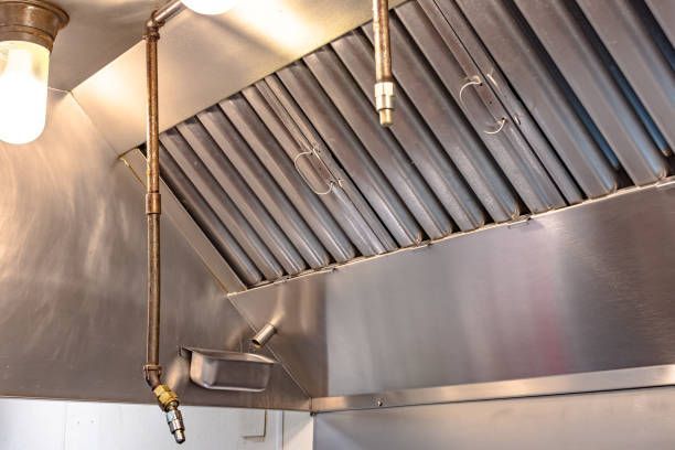 A stainless steel commercial kitchen exhaust hood with integrated fire suppression nozzles and grease baffle filters.