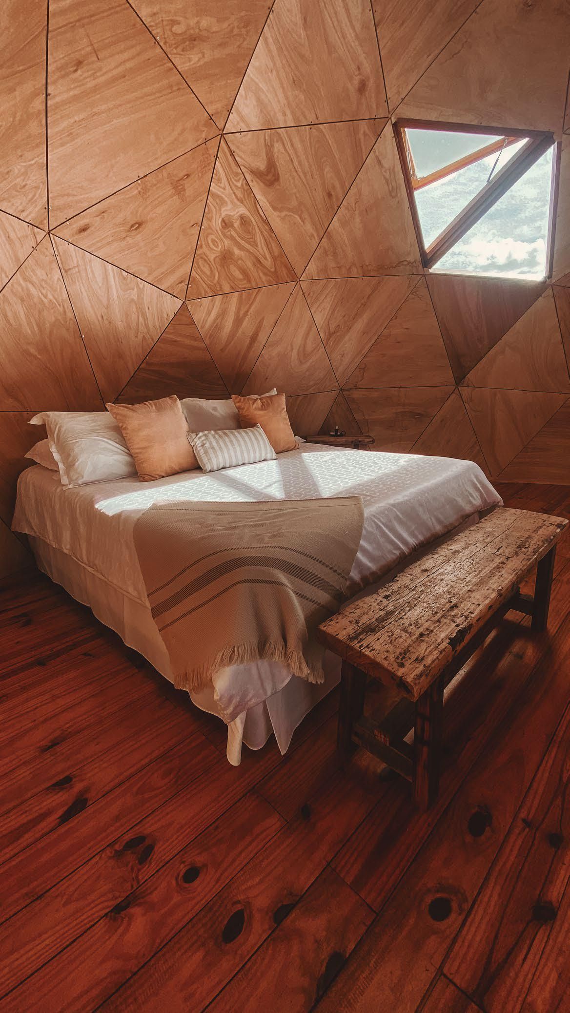 Hay una cama en el medio de la habitación con piso de madera.