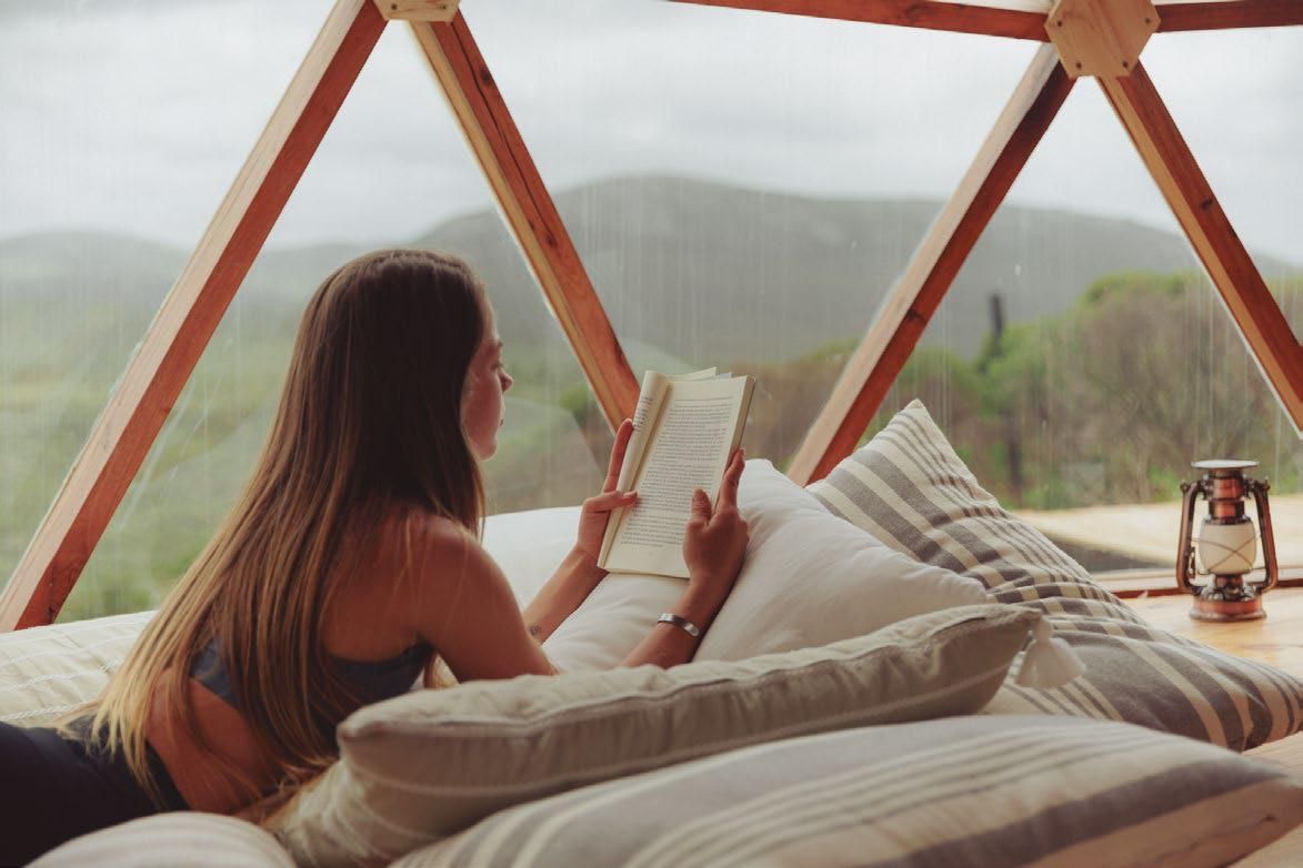 Una mujer está acostada en una cama leyendo un libro.