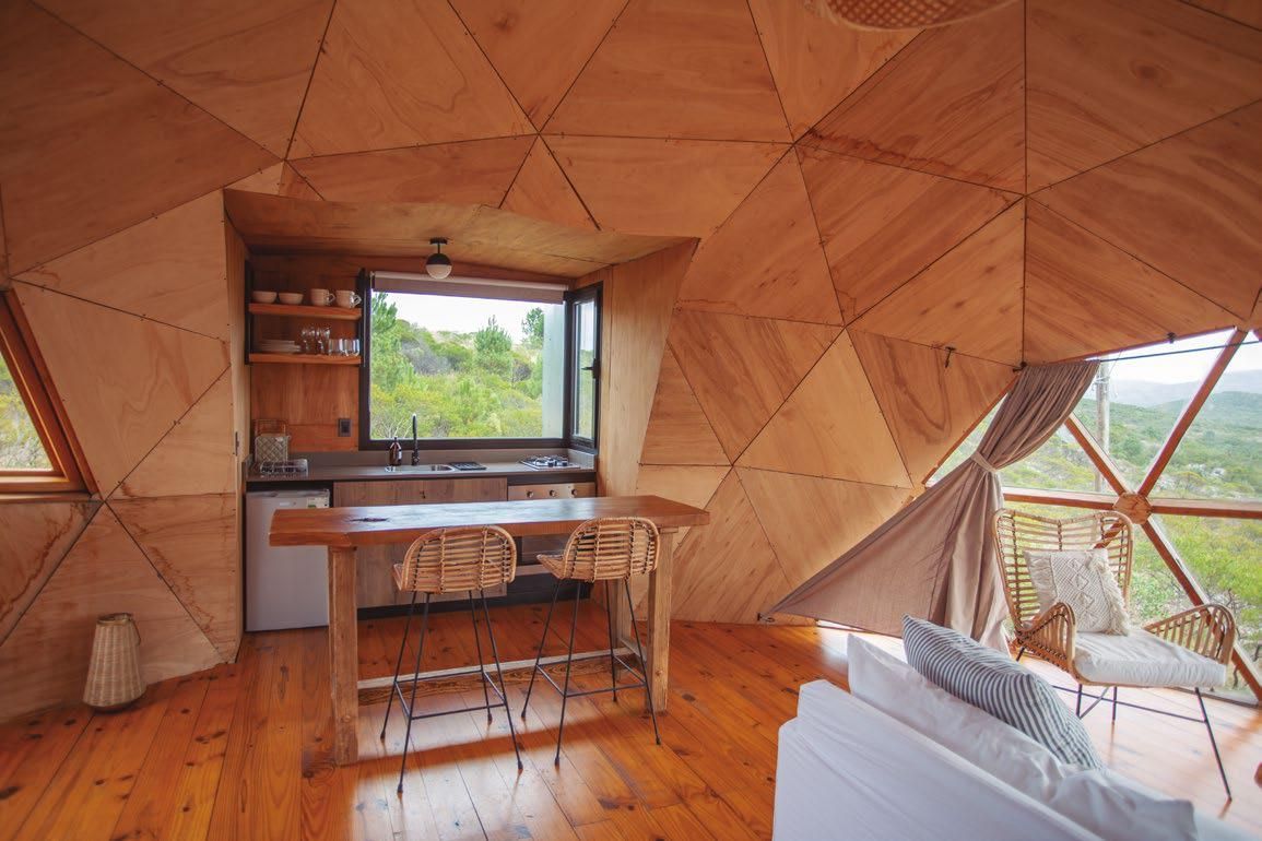 Un salón con sofá, mesa y sillas en una cúpula de madera.