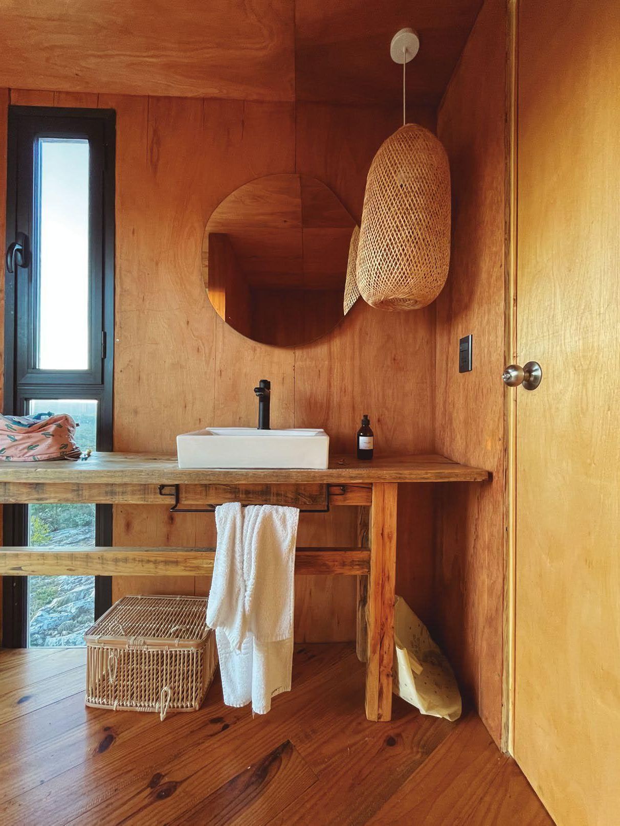 Un baño con lavabo, espejo y piso de madera.