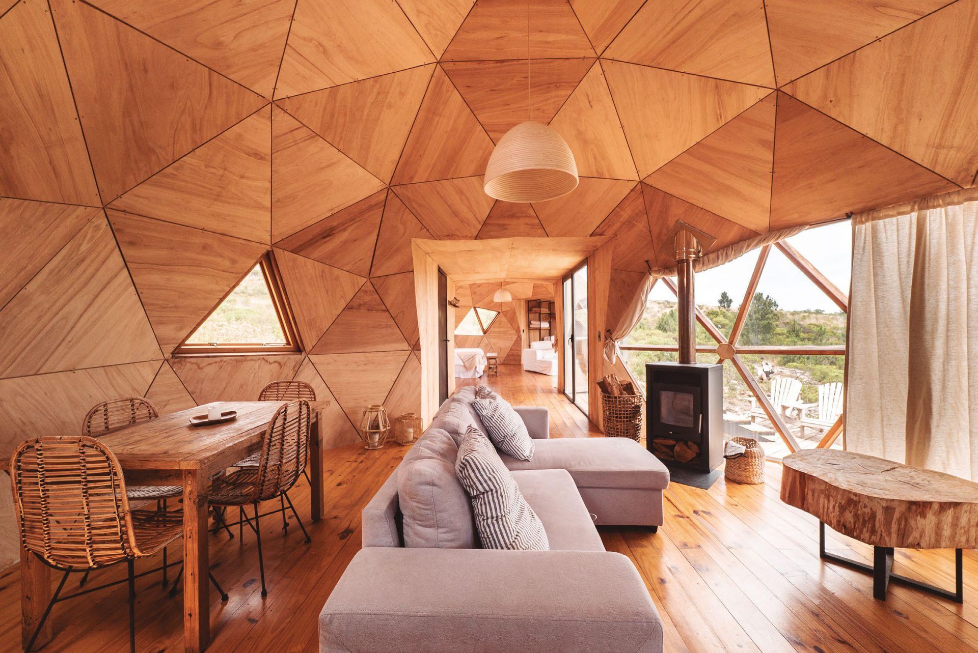 Una sala de estar con sofá, mesa y sillas en una casa con forma de cúpula.