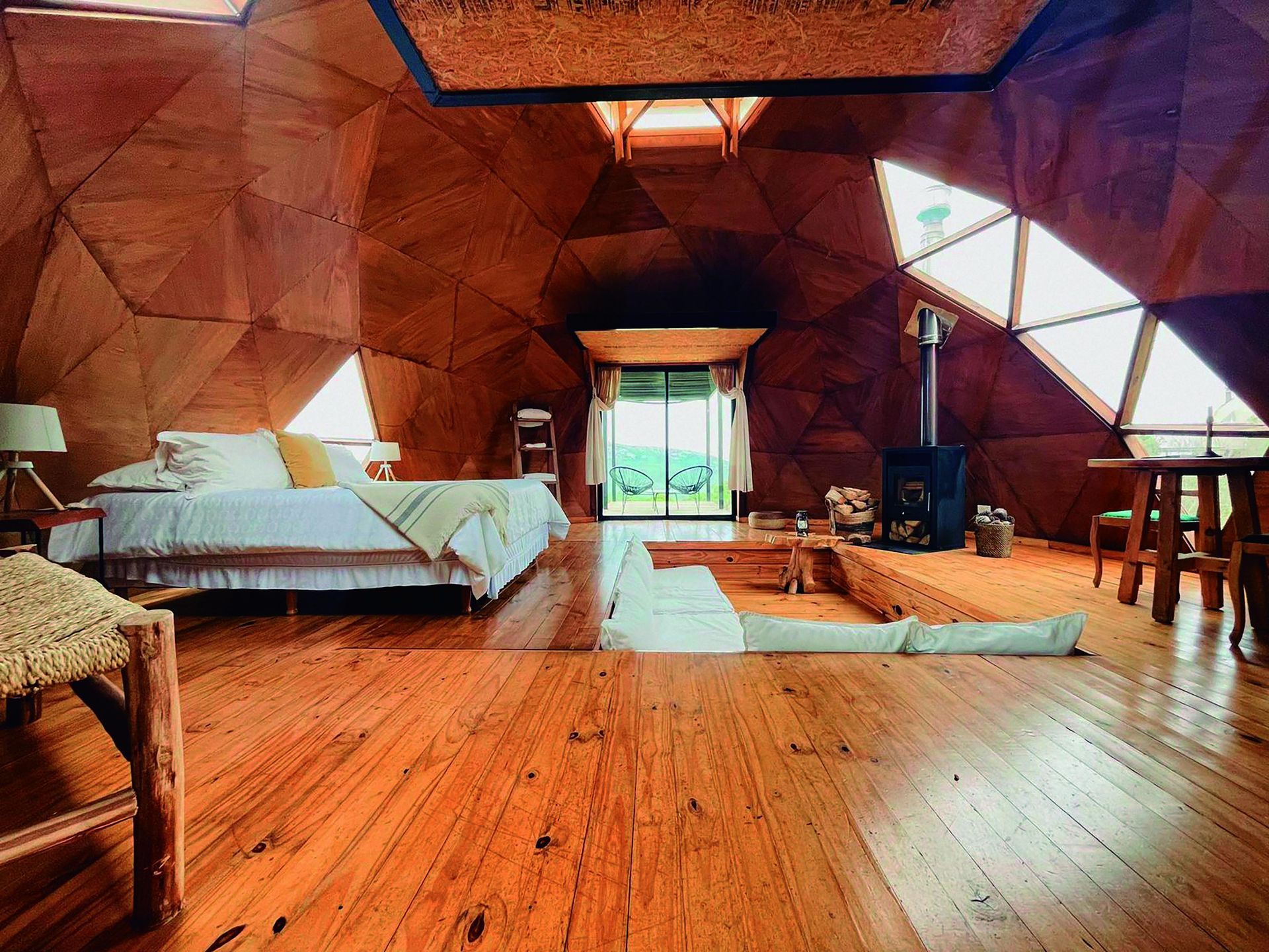 Un dormitorio en una cúpula con piso de madera y una cama.