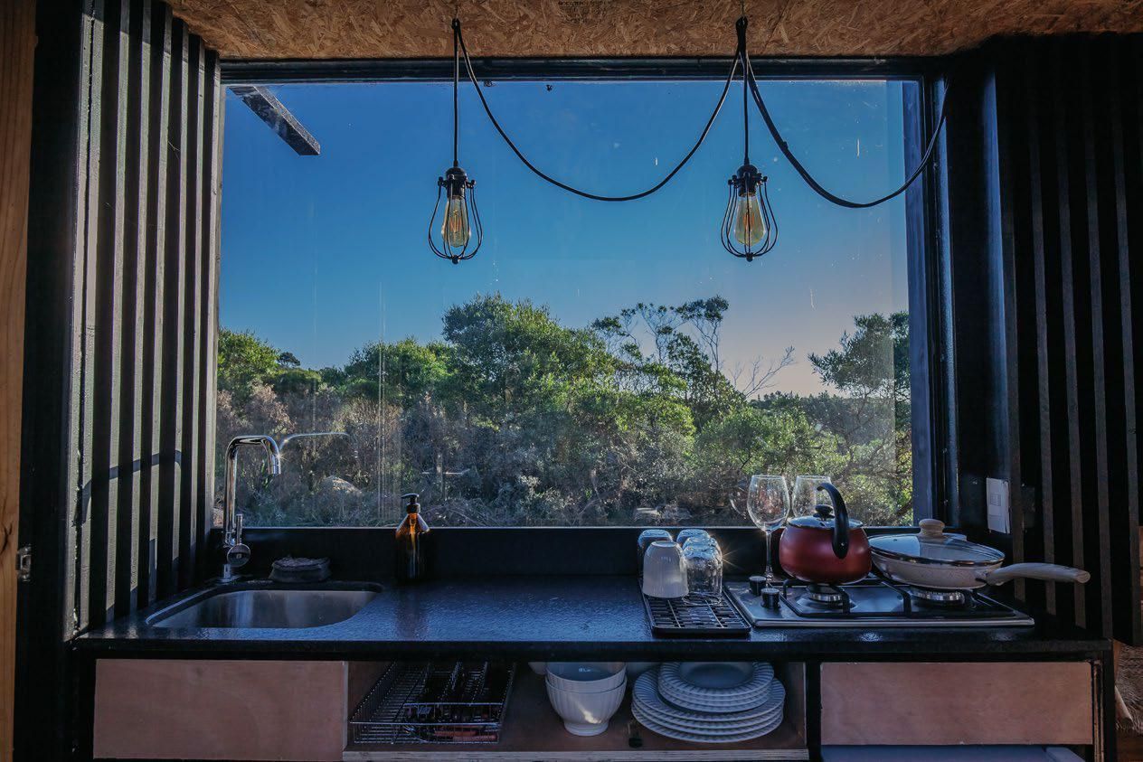 Una cocina con fregadero, estufa y ventana con vista a los árboles.
